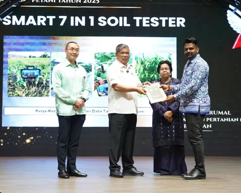 Receiving the award on stage, under a screen that reads Smart 7 in 1 Soil Tester