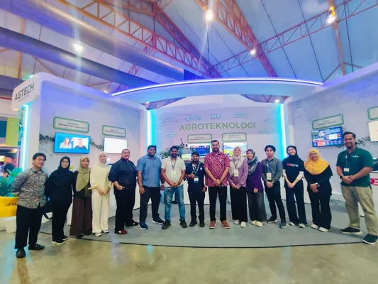 A group photograph in front of the Agroteknologi wall of the MDEC pavilion