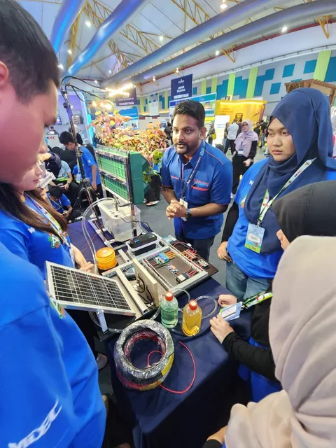 A presenter explaining a solar-powered control prototype to students in Agrovator@Sekolah shirts